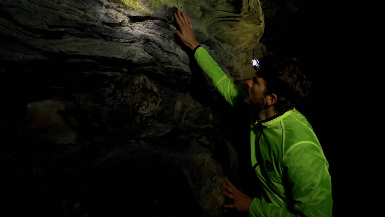 Male hiker exploring a dark cave 4k
