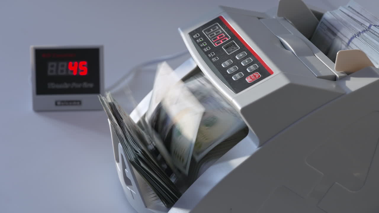 Man puts a big wad of hundred dollar notes into money counting machine. Side view. White background.