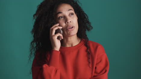 una mujer afroamericana usando un teléfono inteligente sobre un fondo azul.