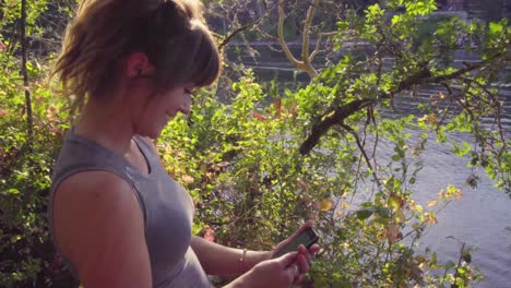 Cute-hipster-girl-candidly-laughing,-dancing,-and-talking-while-looking-at-her-green-screened-phone