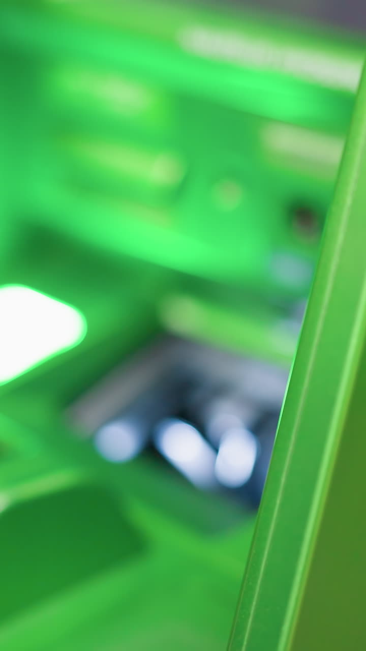 vista de una mano con pulseras de cuentas y una camisa negra recogiendo dinero de un cajero automático verde. disparado con una cámara de mano, capturando el momento de retirar dinero de un caixeo automático