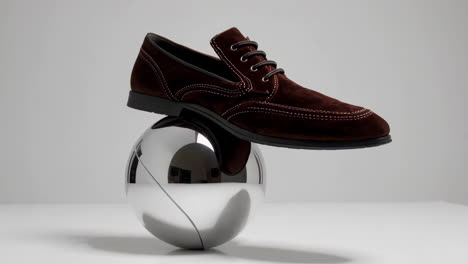 brown suede shoe balancing on a silver sphere