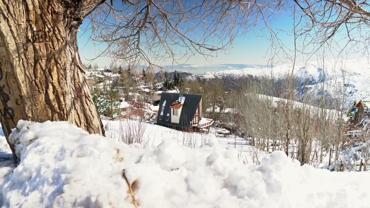 vista estableciendo de mano desde una cabaña en medio de un paisaje completamente cubierto de nieve en el pueblo montañoso de farellones, chile