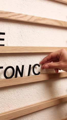 person arranging letters on a wooden wall calendar