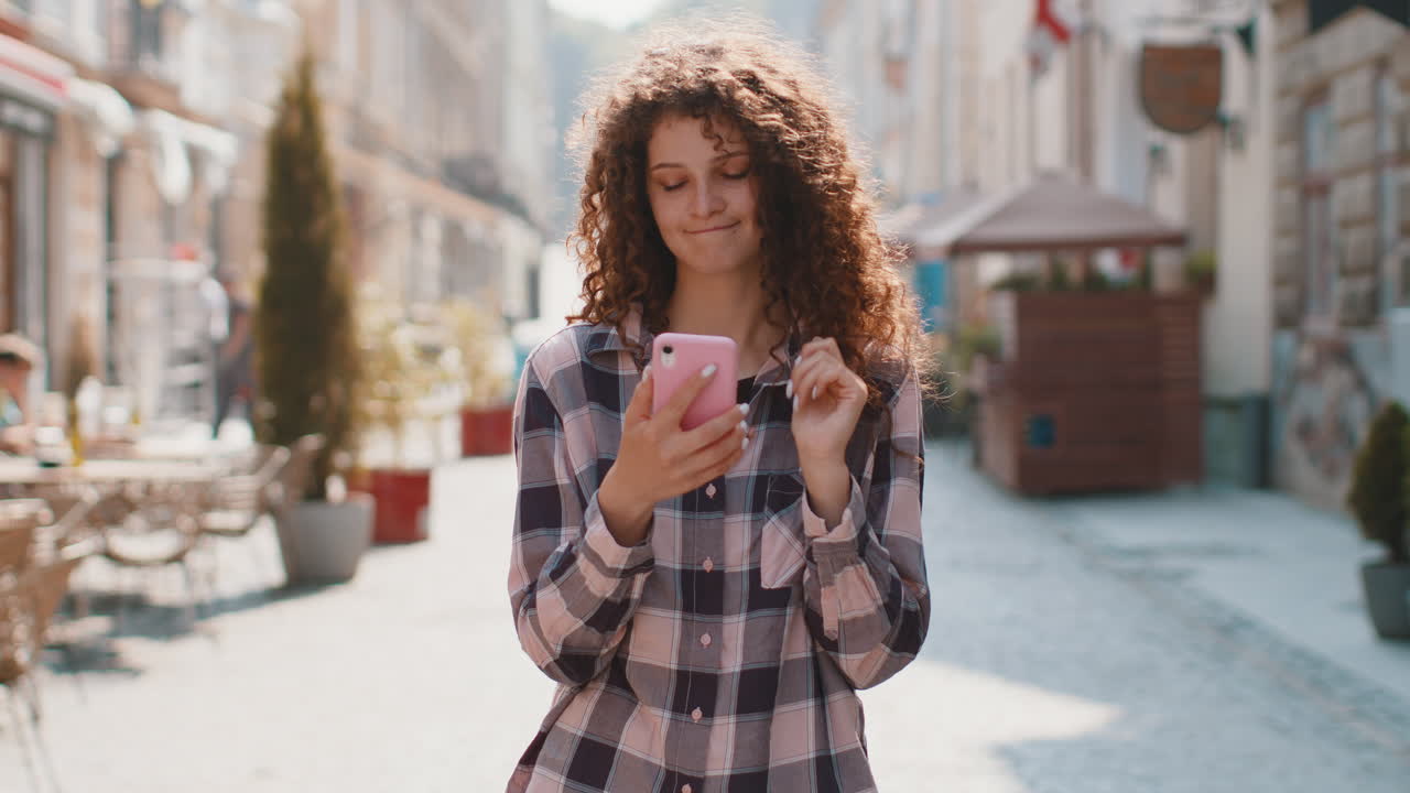 Giovane donna usa lo smartphone, scrive messaggi di testo, naviga su Internet, finisce il lavoro guardando la telecamera.