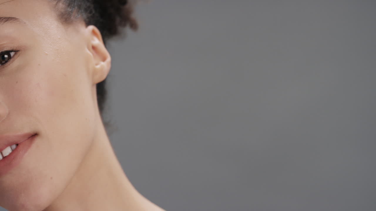 retrato de belleza de mujer tocando la piel con una flor de orquídea acariciando una piel suave y saludable disfrutando de una fragancia natural sensual una mujer joven coqueta sobre un fondo gris concepto de cuidado de la piel