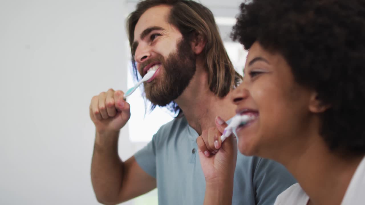 ein gemischtes paar, das sich im badezimmer bürstet