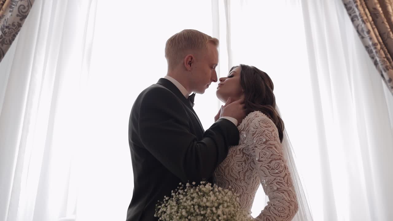 retrato de recién casados, novio caucásico novia caminando, abrazándose, abrazándose en una habitación grande, pareja de bodas