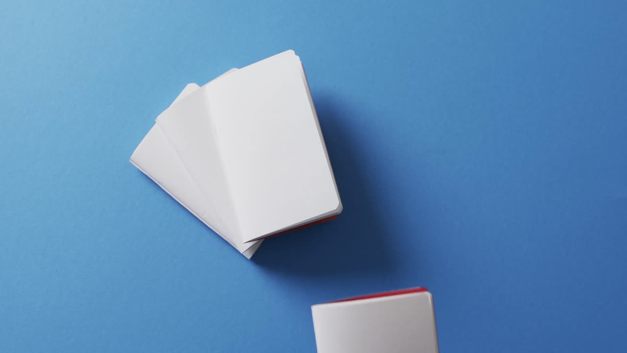 mano sosteniendo un pedazo de papel sobre pedazos de papel con espacio de copia en fondo azul en cámara lenta