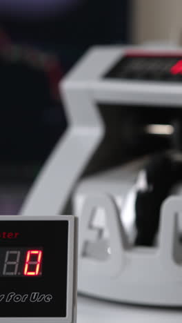 white compact money-counting machine working. fifty euro banknotes calculated in the equipment. close up. blurred backdrop. vertical video