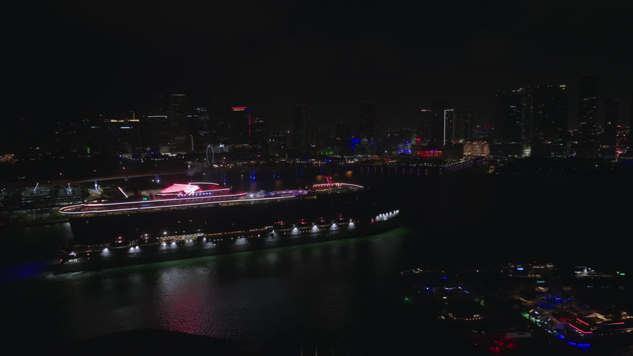 조명이 켜진 고층 빌딩의 스카이라인을 배경으로 시내 항구에 있는 유람선의 공중 야경