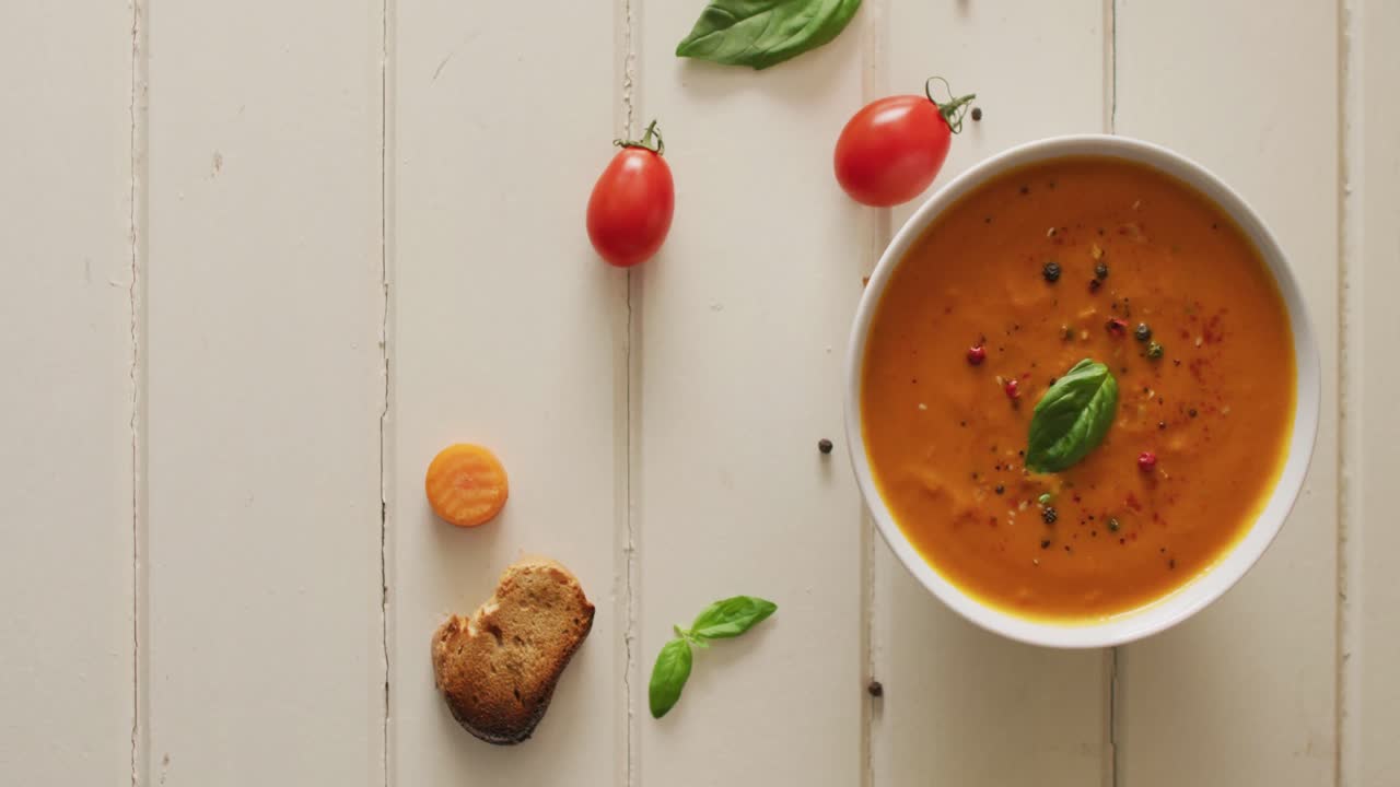 Video of cream tomato soup with ingredients lying on white surface