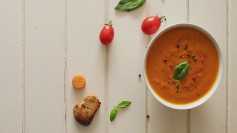 video of cream tomato soup with ingredients lying on white surface