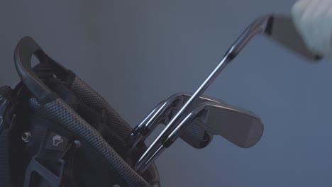 golfer wearing golf glove, removing a 5 iron from his bag to use for his next shot