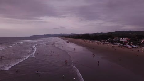Clima-Nublado-En-La-Playa-En-Olón,-Ecuador---Gente-Nadando-Y-Relajándose---Drone-Aéreo