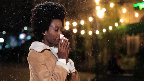 close-up view of sick african american woman in red coat blowing her nose on the street while it¬¥s snowing in christmas