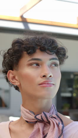 vertical video: confident person with curly hair and scarf looking thoughtfully at home