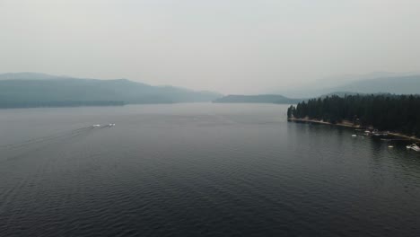 Zoom-out-drone-shot-of-Lake-Payette-in-McCall,-Idaho-on-a-smoky-summer-day