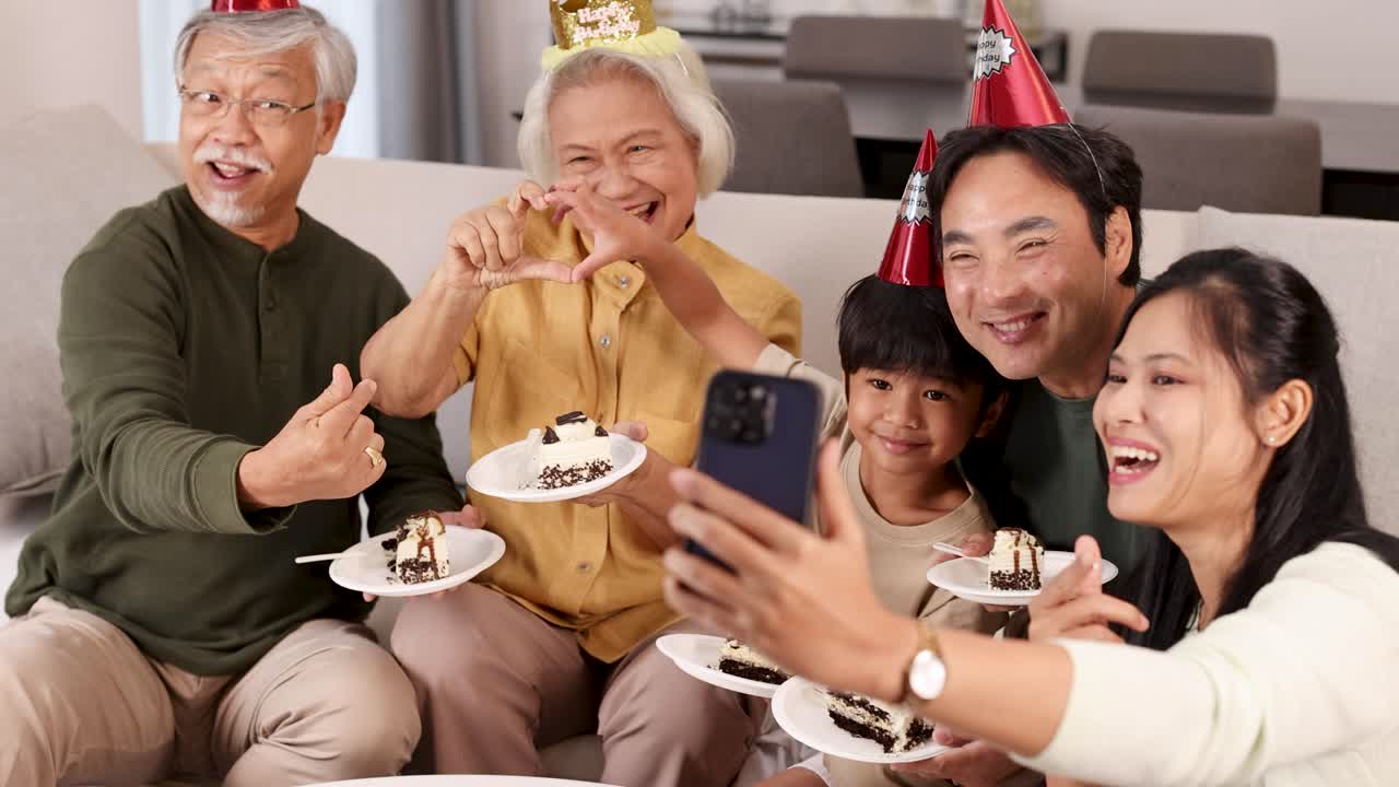 A joyful family captures a birthday moment with cake and selfies. Bright lighting and cheerful expressions create a warm atmosphere