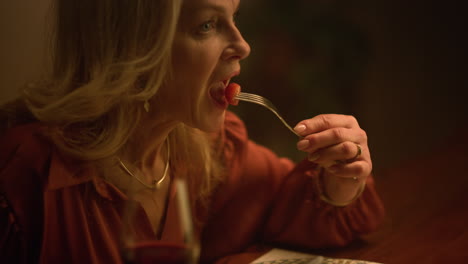 una mujer mayor sonriente comiendo en casa.