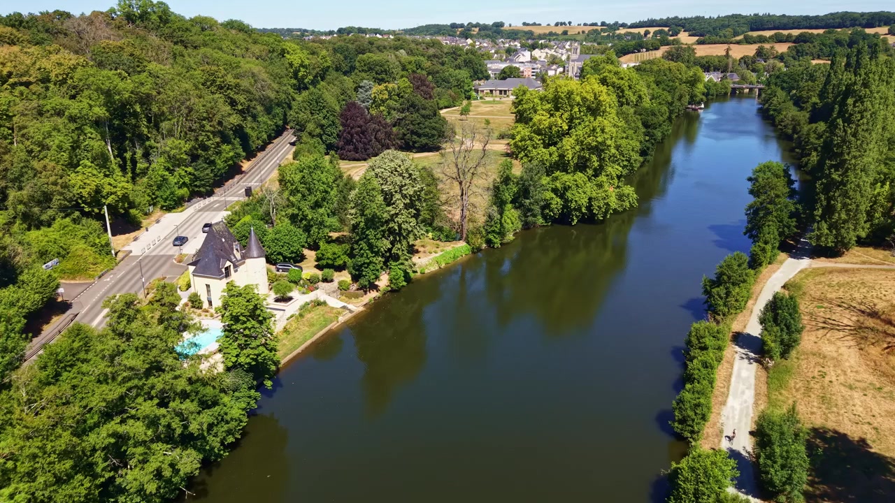 Mayenne-elven renner langs Parc des Ondines og Saint Peter Church i Changé, Mayenne, Pays de la Loire, Frankrike, omkranset av elveskog, elvepromenade og boligområder – luftfoto