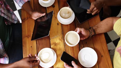 group of friends using mobile phone and digital tablet while having cup of coffee