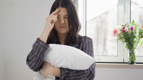 Mujer-Soñadora-Sentada-En-Una-Cama-Y-Abrazando-Una-Almohada-Por-La-Mañana,-De-Cerca