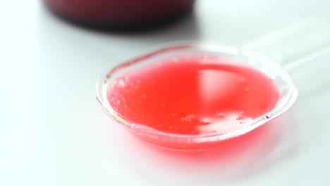 medicamento líquido rojo en cuchara medida