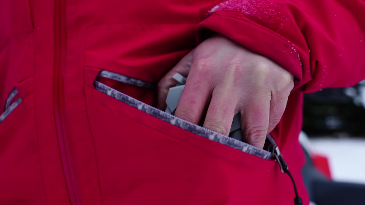 User Storing Drone in Pocket After Flight in Snowy Conditions