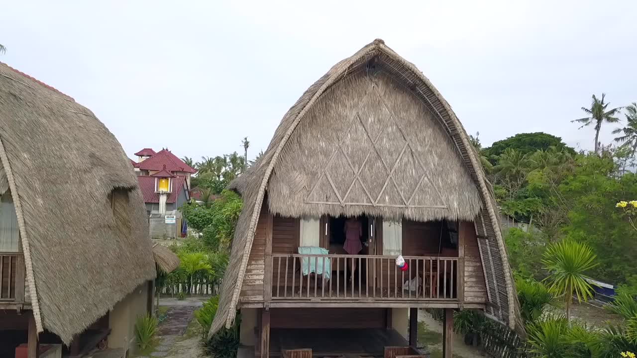 impresionante vista aérea vuelo panorama curva vuelo drone imágenes de una niña en una cabaña de playa lokal bali