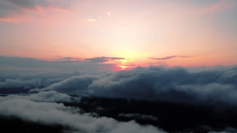 sunrise in mountains with clouds in the foreground and thick fog in the morning