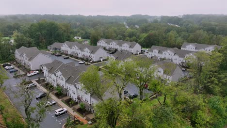 Aerial establishing shot of new modern residential area with grey architectural homes in forest landscape