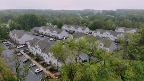 aerial establishing shot of new modern residential area with grey architectural homes in forest landscape