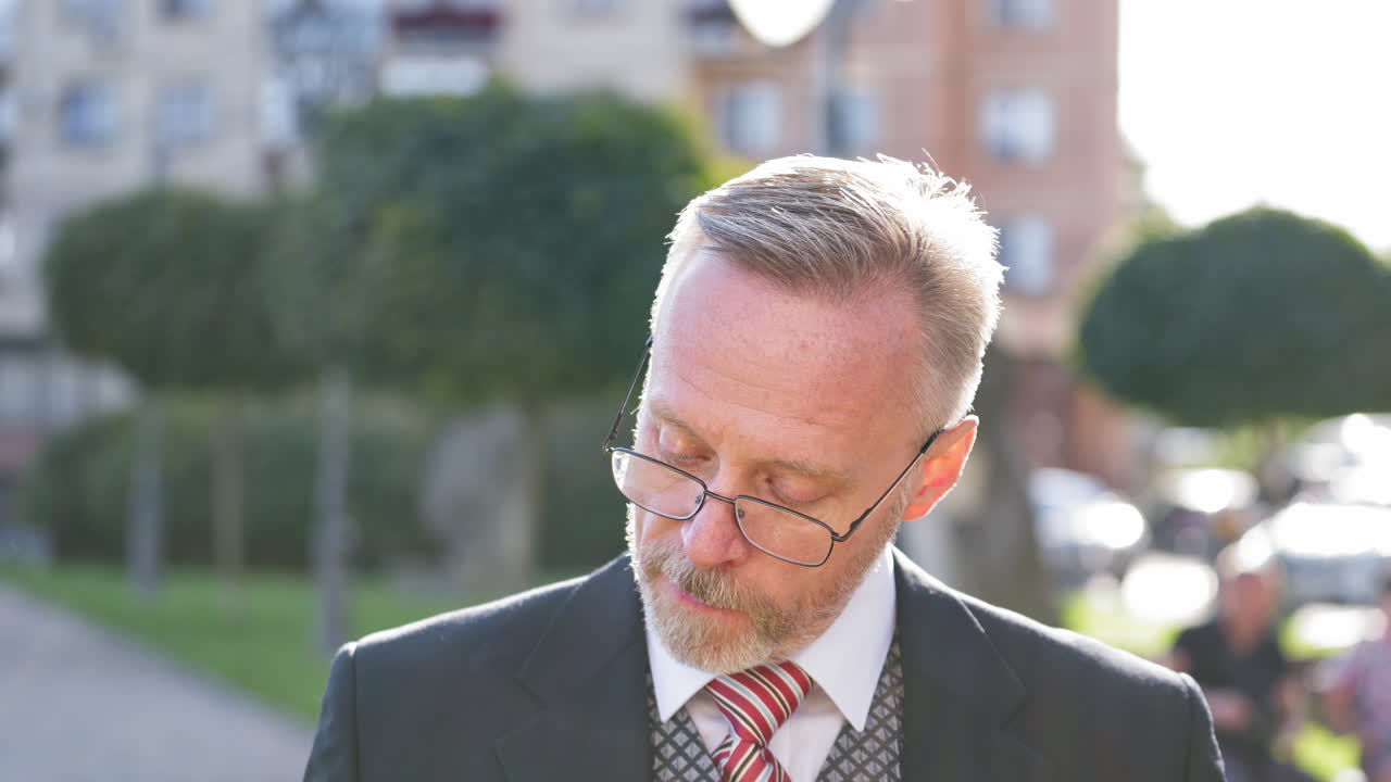 Portrait of senior businessman smoking a cigarette. Mature man wearing tie and costume stands outdoors and smoke. Middle aged businessman thinking about something nervously.