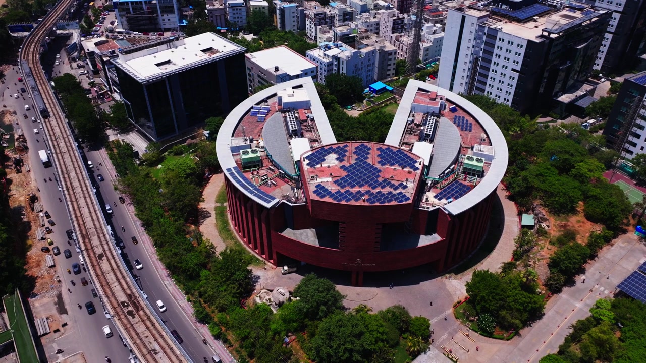 Comboio do metro a mover-se em frente ao edifício TCS Deccan Park com fluxo de tráfego e edifício Maximus 2B na hitec city, madhapur, hyderabad, telangana, índia. Durante o dia, plano estático, plano de drone, 4k