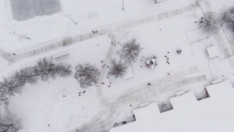 kids enjoy white winter day in kindergarten yard, aerial top down ascend shot