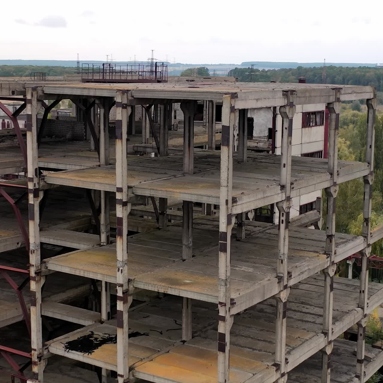 Old factory buildings in rural place. Abandoned territory with ruined warehouses without windows among green nature