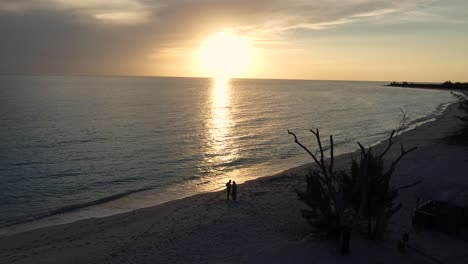 couple stands alone on the beach and enjoys the beautiful sunset