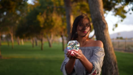 una hermosa hechicera sosteniendo una mágica bola de cristal brillante con una mirada encantadora y misteriosa