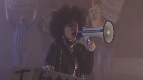 Diverse-group-of-people-wearing-face-masks-holding-protest-signs-shouting-into-megaphone