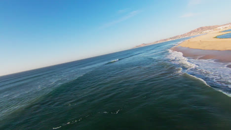 fpv drone shot over coastal sandy beach and ocean in baja region mexico, flying fast along shore and turquoise sea water, seaside landscape