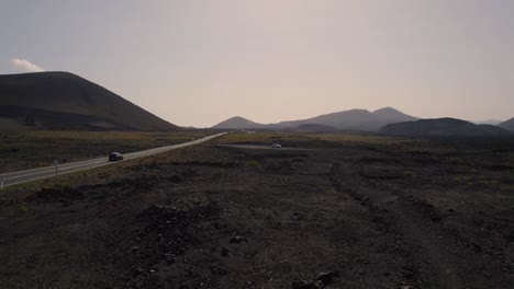 Timanfaya-long-straight-Lanzarote-road,-Canary-islands-volcanic-mountain-landscape-establishing-aerial-view