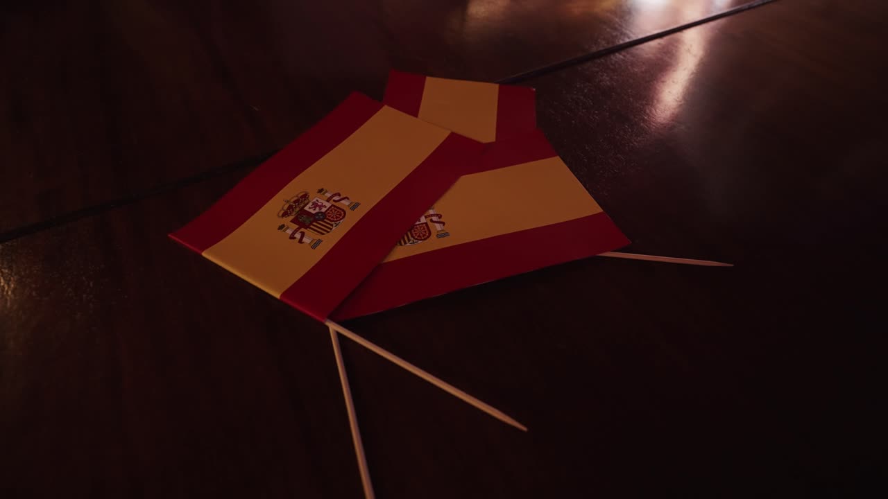 Small Spanish flag paper decorations with toothpicks placed on a polished wooden table