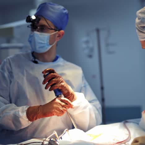 experienced surgeon in neurosurgery operation room with pfrofessional up to date instruments in hands. doctor in scrubs, latex glasses and surgery glasses