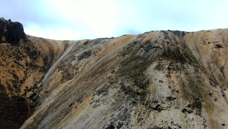 drone flying towards striped mountain rock in the andes, south america