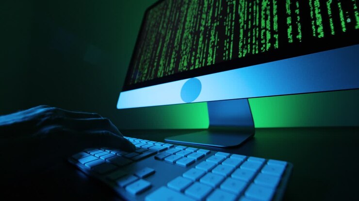 Hands typing on a keyboard and green code on a screen.