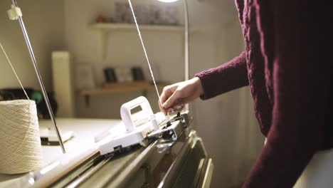 mujer creativa que prepara una máquina de tejer para trabajar en un taller textil