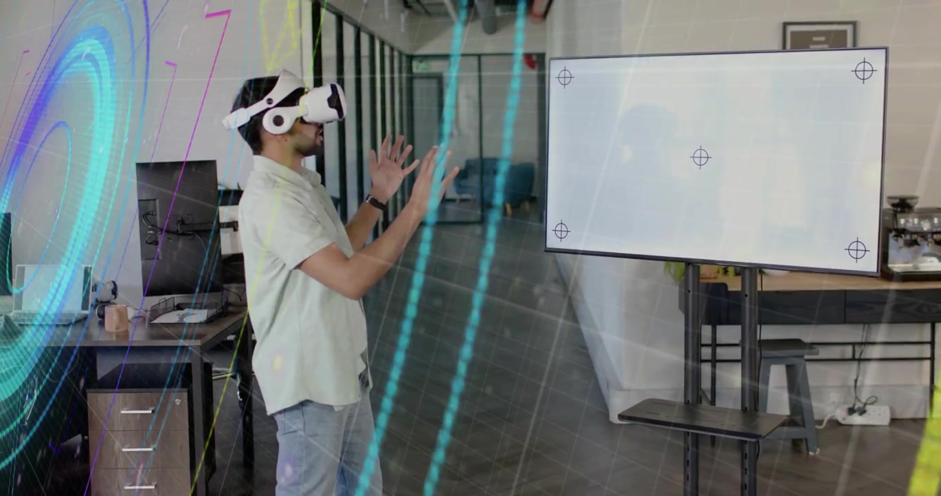 Uomo che indossa un visore VR, avviando grafici olografici a colori in un ufficio tecnologico con interfaccia utente.