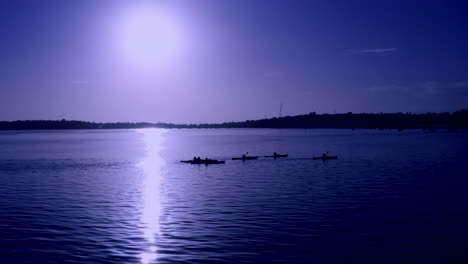 people kayaking on the lake during blue hour with full moon on the background in auckland, new zealand