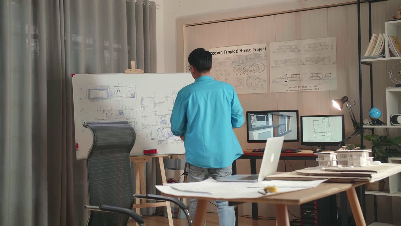Asian Man Engineer With A Laptop Drawing Blueprint On The Whiteboard At The Office